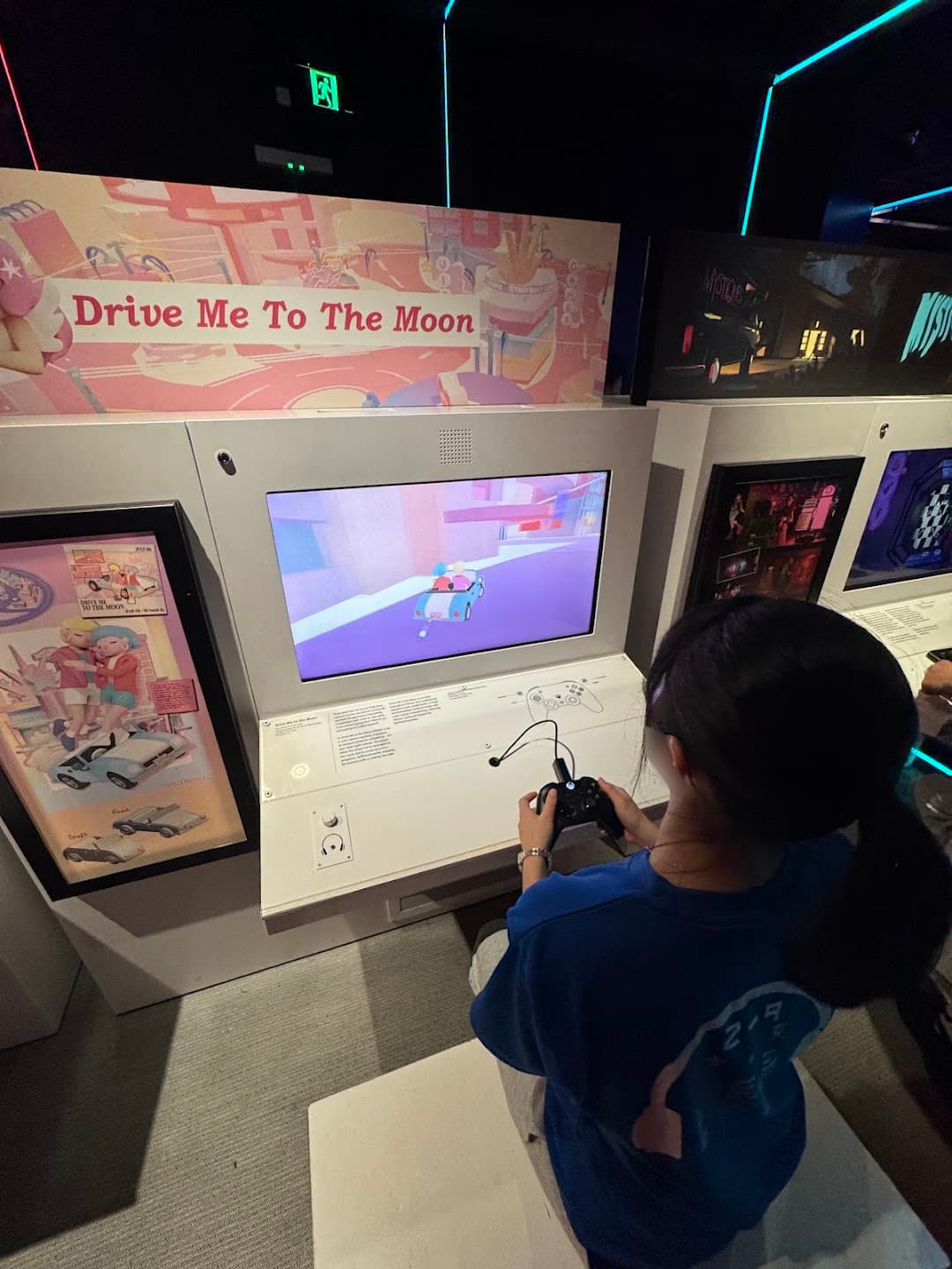 ACMIのゲーム展示で、画面を見ながらコントローラーを操作する